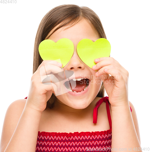 Image of Little girl is holding hearts over her eyes