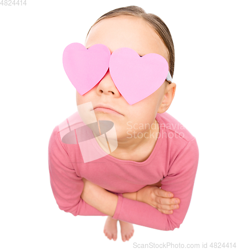 Image of Little girl is holding hearts over her eyes