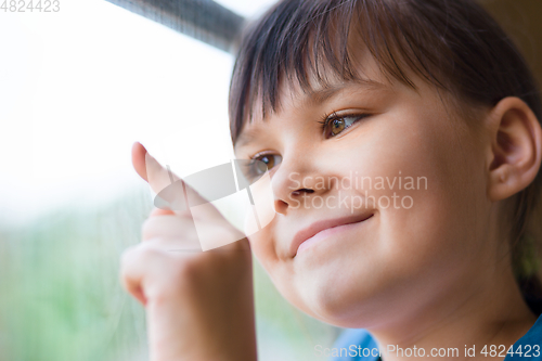 Image of Happy girl is drawing something on window