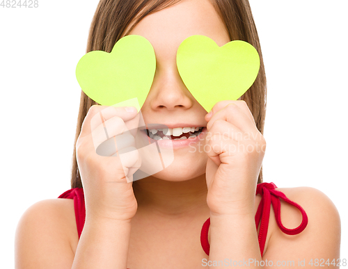 Image of Little girl is holding hearts over her eyes
