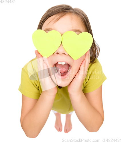 Image of Little girl is holding hearts over her eyes