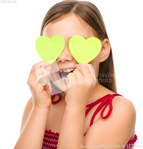 Image of Little girl is holding hearts over her eyes