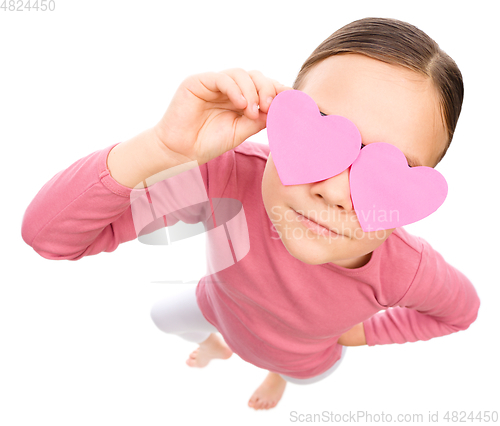 Image of Little girl is holding hearts over her eyes