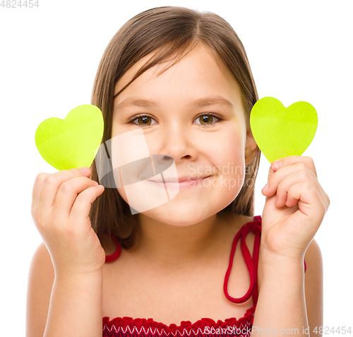 Image of Little girl is holding hearts near her eyes