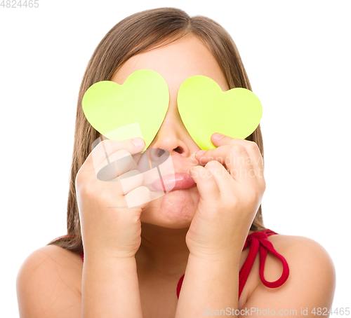 Image of Little girl is holding hearts over her eyes