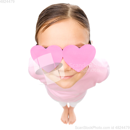 Image of Little girl is holding hearts over her eyes