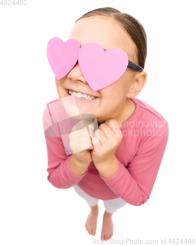 Image of Little girl is holding hearts over her eyes