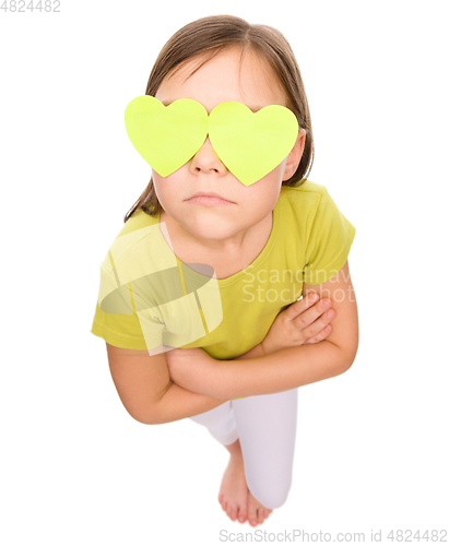 Image of Little girl is holding hearts over her eyes