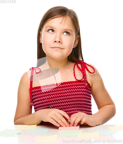 Image of Girl is writing on color stickers using pen