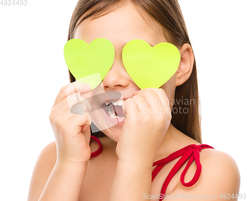 Image of Little girl is holding hearts over her eyes