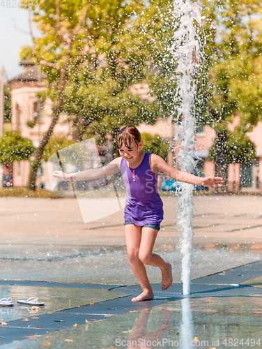 Image of Girl is enjoying fountain with cold water