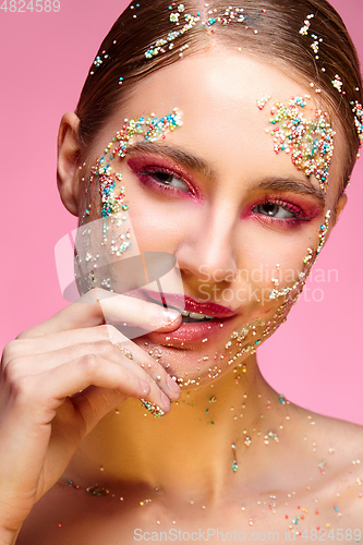 Image of beautiful girl with candies on pink backgroound