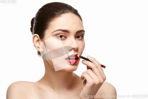 Image of girl applying red lipstick isolated on white