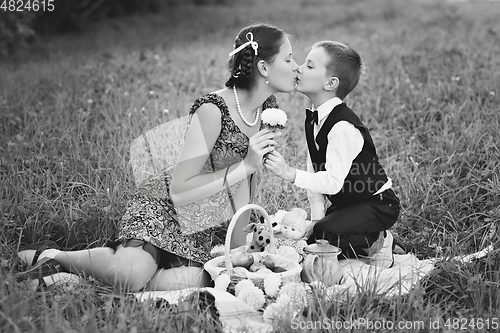 Image of Little boy and teen age girl having picnic outdoors