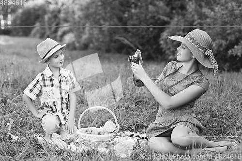 Image of Little boy and teen age girl having picnic outdoors