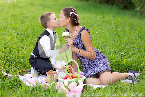 Image of Little boy and teen age girl having picnic outdoors
