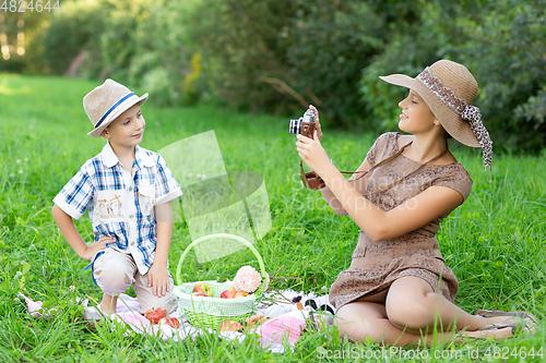 Image of Little boy and teen age girl having picnic outdoors