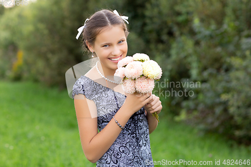 Image of beautiful teen age girl holding flowers outdoors