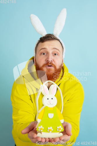 Image of Easter bunny man with bright emotions on blue studio background