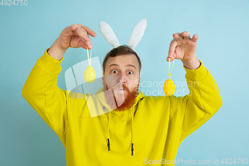 Image of Easter bunny man with bright emotions on blue studio background