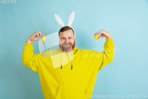 Image of Easter bunny man with bright emotions on blue studio background