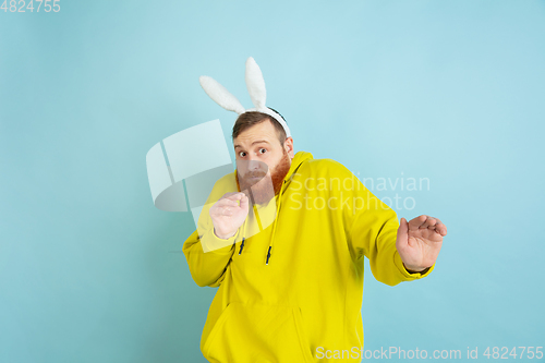 Image of Easter bunny man with bright emotions on blue studio background