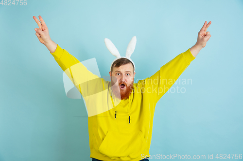 Image of Easter bunny man with bright emotions on blue studio background