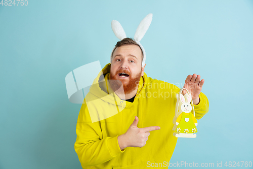 Image of Easter bunny man with bright emotions on blue studio background