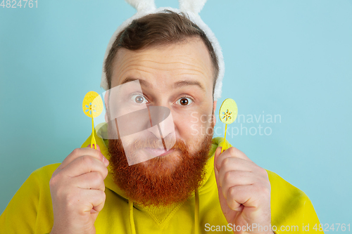 Image of Easter bunny man with bright emotions on blue studio background