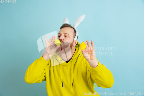 Image of Easter bunny man with bright emotions on blue studio background