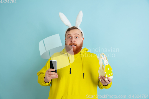 Image of Easter bunny man with bright emotions on blue studio background