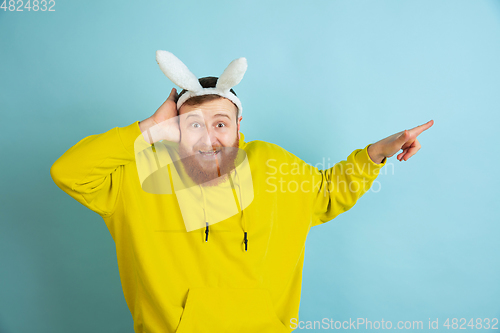 Image of Easter bunny man with bright emotions on blue studio background