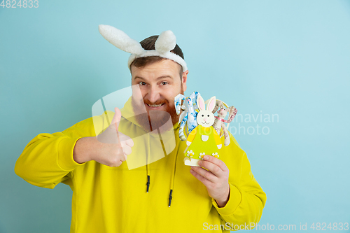 Image of Easter bunny man with bright emotions on blue studio background