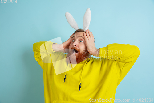 Image of Easter bunny man with bright emotions on blue studio background