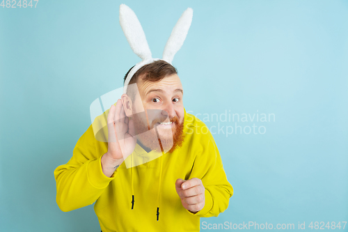 Image of Easter bunny man with bright emotions on blue studio background