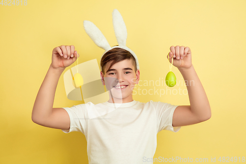 Image of Easter bunny boy with bright emotions on yellow studio background