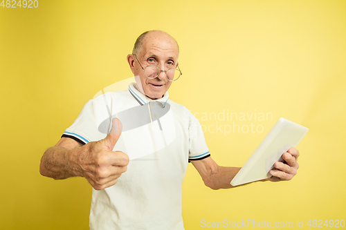 Image of Caucasian senior man\'s portrait isolated on yellow studio background