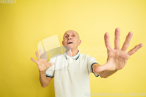 Image of Caucasian senior man\'s portrait isolated on yellow studio background