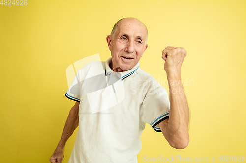 Image of Caucasian senior man\'s portrait isolated on yellow studio background