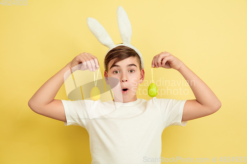 Image of Easter bunny boy with bright emotions on yellow studio background