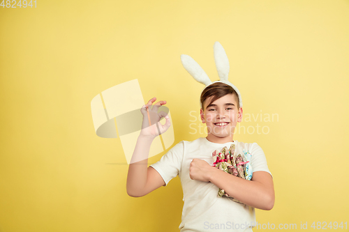 Image of Easter bunny boy with bright emotions on yellow studio background