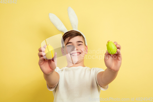 Image of Easter bunny boy with bright emotions on yellow studio background