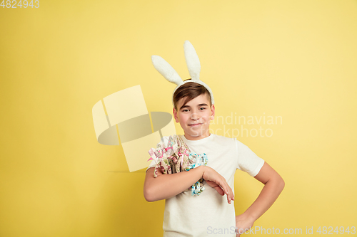 Image of Easter bunny boy with bright emotions on yellow studio background