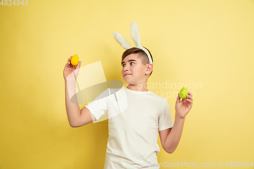 Image of Easter bunny boy with bright emotions on yellow studio background