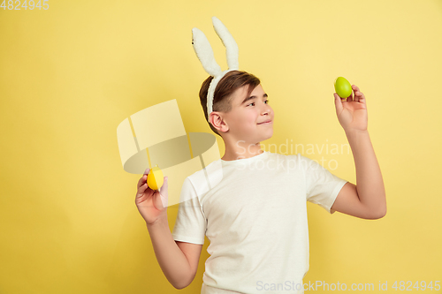 Image of Easter bunny boy with bright emotions on yellow studio background