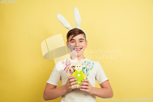 Image of Easter bunny boy with bright emotions on yellow studio background