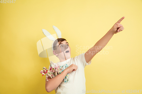 Image of Easter bunny boy with bright emotions on yellow studio background