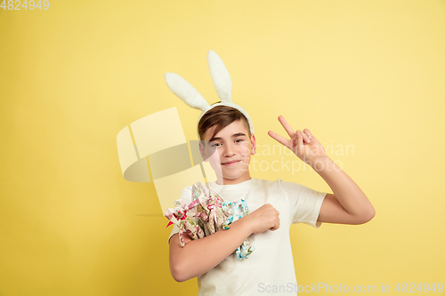 Image of Easter bunny boy with bright emotions on yellow studio background