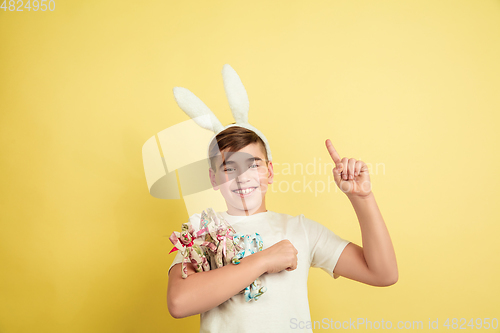 Image of Easter bunny boy with bright emotions on yellow studio background