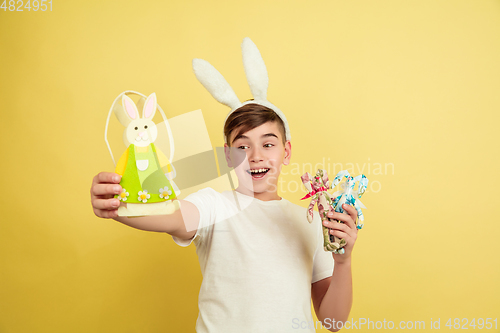 Image of Easter bunny boy with bright emotions on yellow studio background